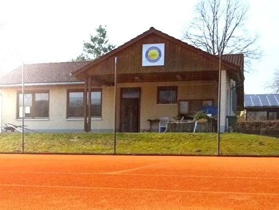 Das Clubheim des TC Malterdingen mit Vereinswappen und Sandplatz davor