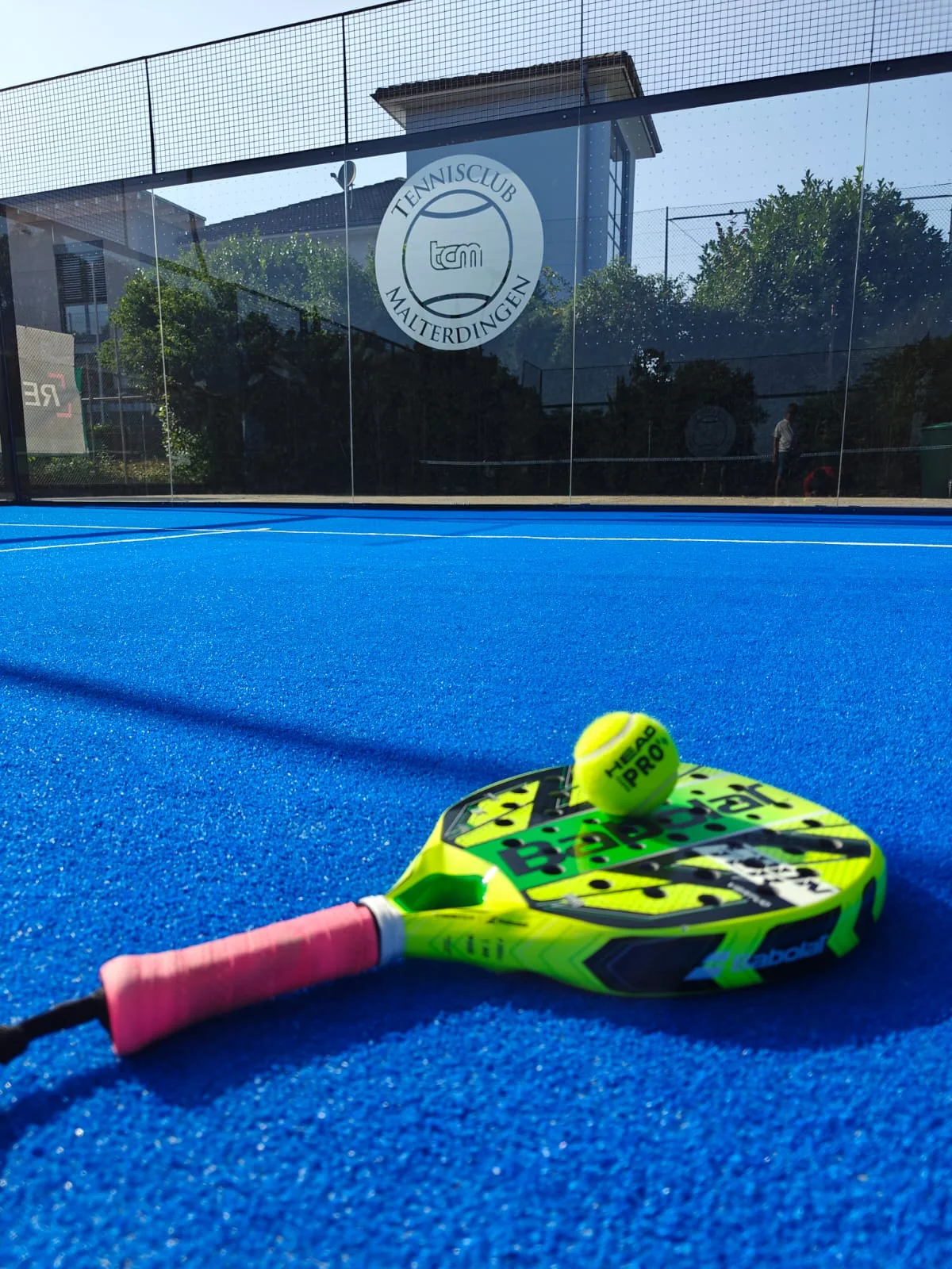 Padelschläger und Ball auf dem blauen Belag des Courts